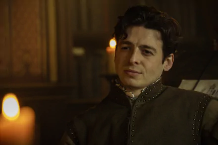 HD desktop wallpaper featuring a character from the TV show Shardlake in a historical costume, seated in a dimly lit room with candles.