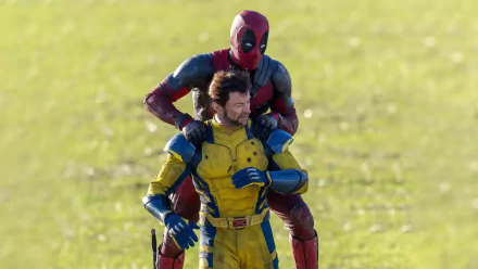 HD wallpaper featuring Deadpool and Wolverine from the movie, showing Deadpool standing behind Wolverine outdoors on a sunny day.