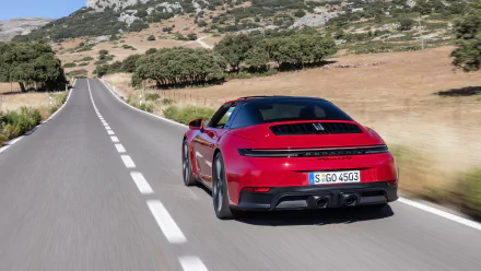 HD desktop wallpaper featuring a red Porsche 911 Targa 4 GTS driving on a scenic, open road surrounded by nature.