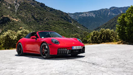 A red Porsche 911 Targa 4 GTS parked on a scenic mountain road, captured as a high-definition desktop wallpaper and background. The car stands out vividly against the lush green hills and blue sky.