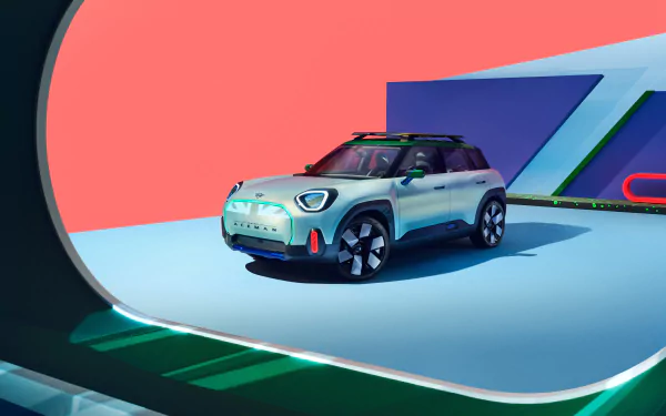 A Mini Aceman car is displayed as a HD desktop wallpaper, featuring the vehicle against a vibrant backdrop with geometric shapes in red, blue, and green tones.