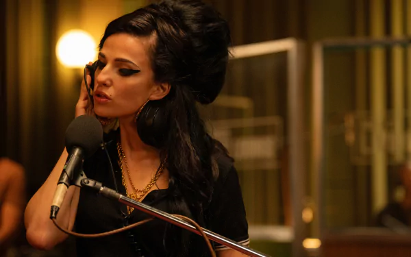 A high-definition desktop wallpaper from the movie Back to Black, featuring Amy Winehouse in a recording studio with her signature beehive hairstyle and makeup, singing into a microphone.