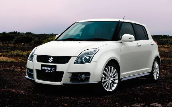 HD desktop wallpaper featuring a white Suzuki Swift Sport car parked on a rugged outdoor terrain under a soft, overcast sky.