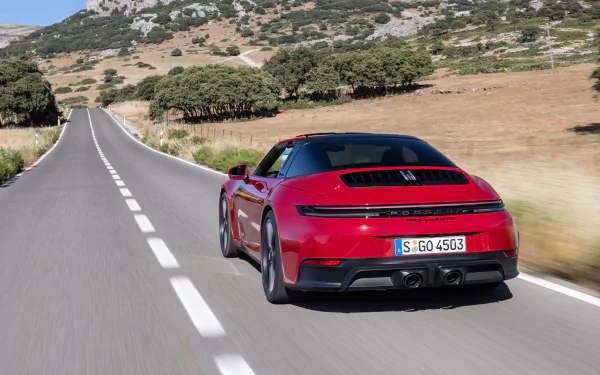HD desktop wallpaper featuring a red Porsche 911 Targa 4 GTS driving on a scenic, open road surrounded by nature.