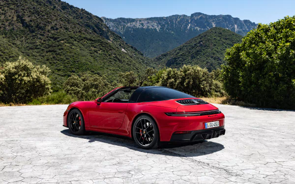 A stunning HD desktop wallpaper featuring a red Porsche 911 Targa 4 GTS parked on a scenic mountain background with lush greenery.