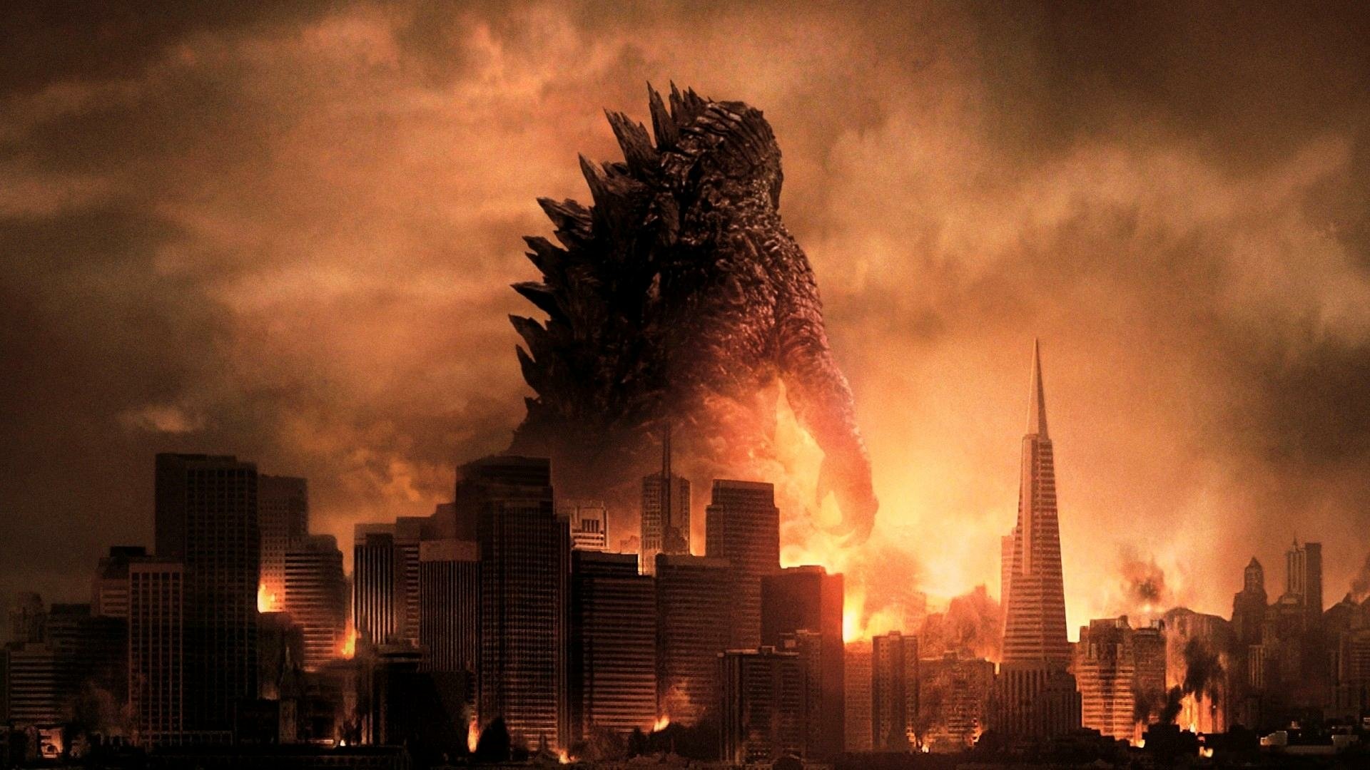 HD PC desktop wallpaper of Godzilla (2014) towering over a city engulfed in fiery smoke under a dramatic, dark orange sky.