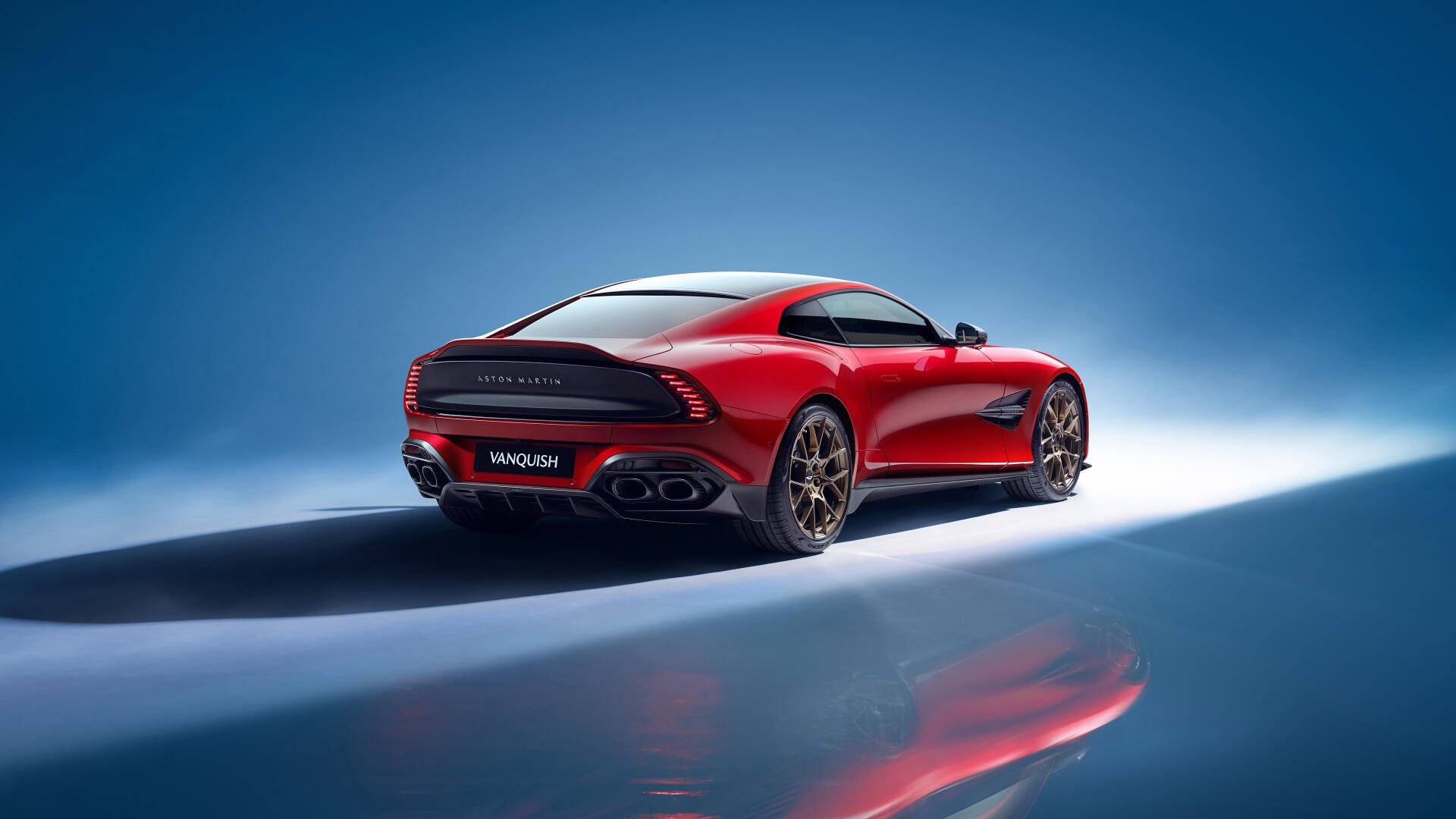 A stunning Aston Martin Vanquish showcased in a striking red color against a vivid blue backdrop, captured in 4K Ultra HD for an impressive desktop wallpaper.