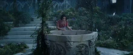 A scene from the movie Snow White (2025) featuring Snow White by a beautifully detailed stone well, surrounded by lush greenery and a serene, enchanting atmosphere.