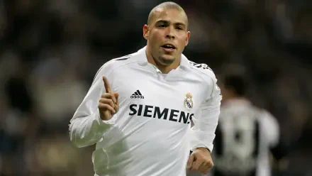 Ronaldo Nazário celebrates a goal while playing for Real Madrid C.F., wearing the iconic white jersey with Siemens, captured in an energetic soccer match moment.