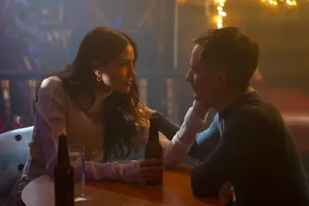 A scene from the TV show La Máquina (2024), featuring two characters in an intimate conversation at a bar, with warm lighting and drinks on the table.