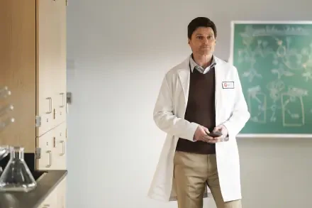 A scene from the TV show Tracker (2024), featuring a person in a lab coat standing in a classroom with a chalkboard, showcasing a blend of professionalism and intrigue.