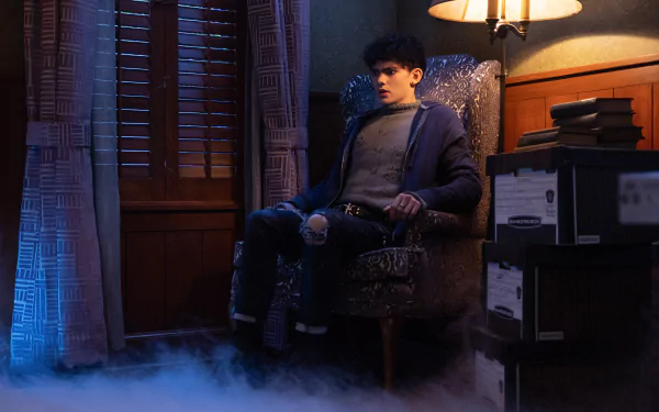 A moody HD desktop wallpaper featuring a character sitting in a vintage armchair, surrounded by fog and shadows, capturing the eerie vibe of Agatha All Along.