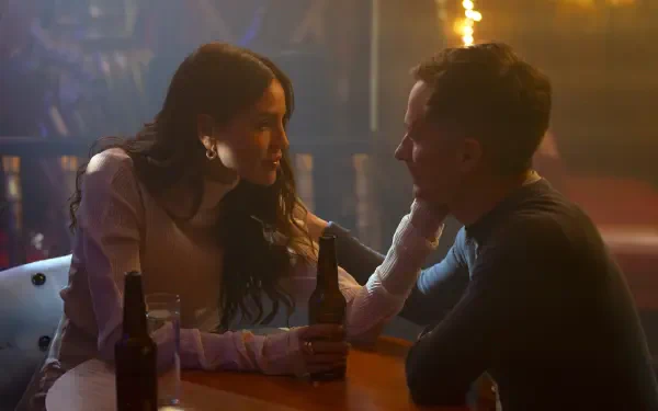 A scene from the TV show La Máquina (2024), featuring two characters in an intimate conversation at a bar, with warm lighting and drinks on the table.