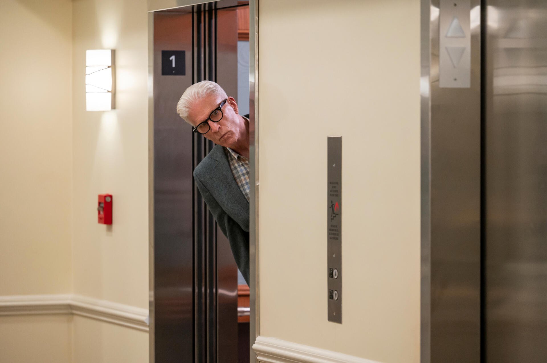 A scene from the TV show A Man on the Inside features Ted Danson peeking out from an elevator, adding a touch of intrigue to this HD desktop wallpaper.