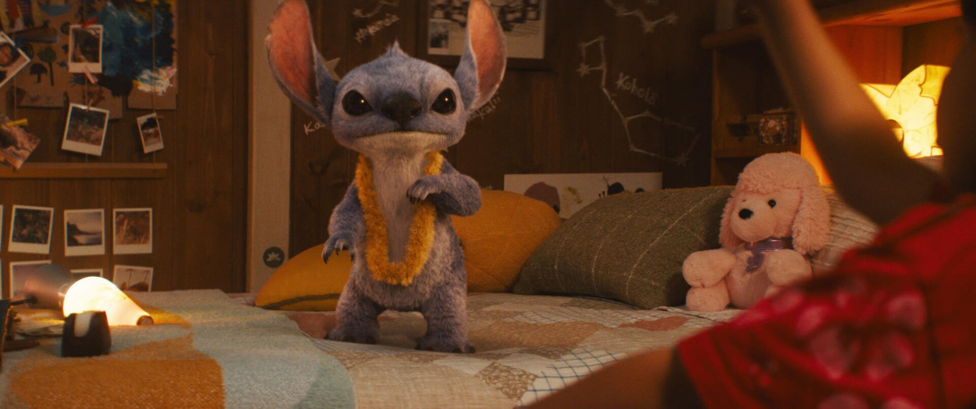 A vibrant HD wallpaper featuring Stitch from Lilo & Stitch (2025), playfully posed on a bed surrounded by colorful bedding and stuffed animals.