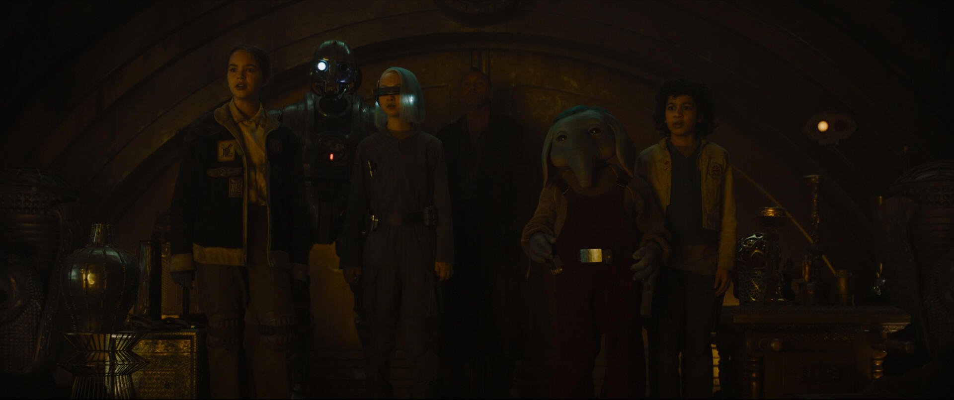 A group of characters from the TV show Star Wars: Skeleton Crew stands together in a dimly lit setting, creating an engaging HD desktop wallpaper and background.