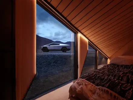 A Tesla Cybertruck is parked outside a modern room, visible through large windows with a dramatic landscape in the background, creating a striking 4K Ultra HD desktop wallpaper.