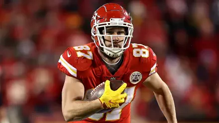 Travis Kelce of the Kansas City Chiefs runs with the football during an NFL game, captured in this dynamic HD desktop wallpaper featuring vibrant team colors.