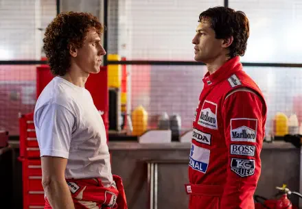 A dynamic scene from the TV show Senna (2024) featuring Ayrton Senna and another character, set in a racing garage, showcasing intense rivalry and emotion.