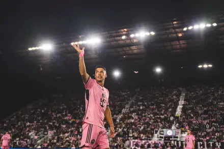 Luis Suárez gestures to fans while playing for Inter Miami CF, illuminated by bright stadium lights in a vibrant atmosphere, captured in stunning 4K Ultra HD detail.
