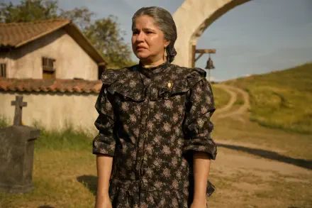 A powerful scene from the TV show One Hundred Years of Solitude, featuring a woman in a vintage dress standing in a rural setting, evoking themes of memory and solitude.
