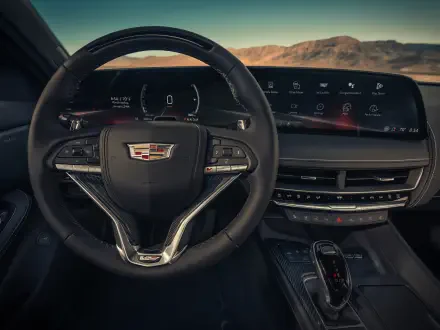 Detailed view of the Cadillac CT5-V Blackwing interior, showcasing the sleek dashboard, steering wheel, and modern technology, set against a stunning outdoor backdrop.