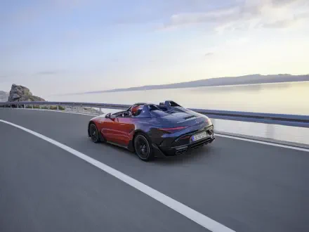 A Mercedes-AMG PureSpeed car driving along a scenic road by the water, showcasing sleek design and performance in a stunning 4K Ultra HD background.