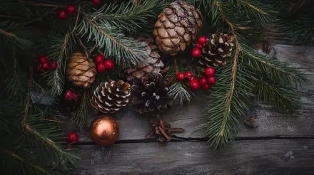 A rustic holiday-themed arrangement featuring pinecones, red berries, and evergreen branches set against a textured wooden background, designed as a 4K Ultra HD desktop wallpaper.