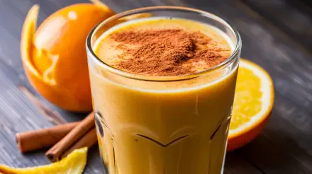 A refreshing smoothie topped with cinnamon, surrounded by fresh oranges and cinnamon sticks, captured in vibrant detail for a 4K Ultra HD desktop wallpaper.