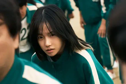 A character from the TV show Squid Game stares intently while wearing a green tracksuit, surrounded by others in a similar outfit, captured in sharp 4K Ultra HD detail.