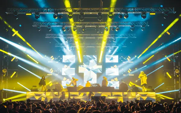 A vibrant EDM concert scene featuring performers on stage illuminated by dynamic lights and visuals, captured in stunning 4K Ultra HD, perfect for a desktop wallpaper or background.