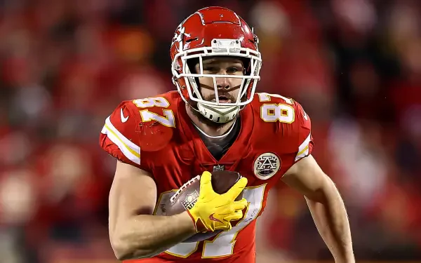 Travis Kelce of the Kansas City Chiefs runs with the football during an NFL game, captured in this dynamic HD desktop wallpaper featuring vibrant team colors.