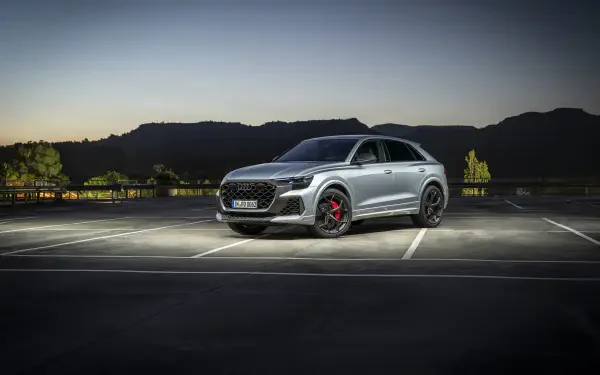 A sleek Audi RS Q8 parked in an empty lot at dusk, highlighted by ambient lighting, showcasing its modern design and powerful stance. 4K Ultra HD wallpaper.