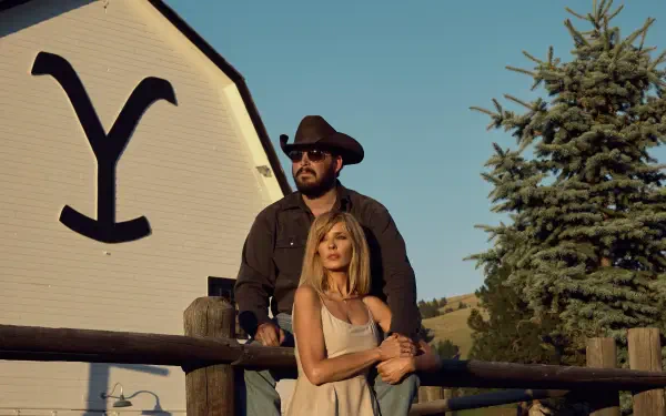 A scene from the TV show Yellowstone, featuring two characters against a backdrop of a barn with a prominent logo, capturing the essence of the series in stunning 4K Ultra HD.