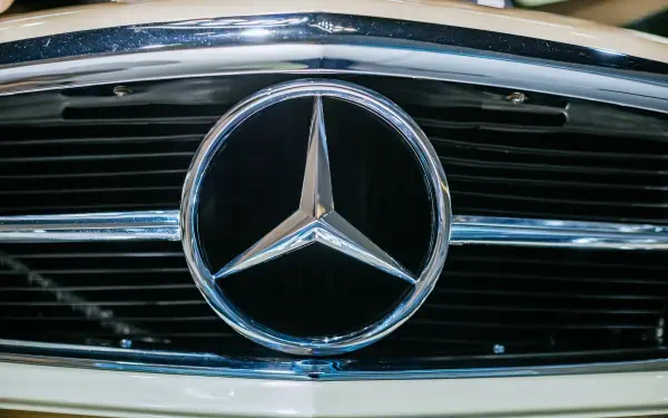 Close-up of the Mercedes-Benz logo on the front grille of a classic Mercedes-Benz 230 SL, showcased in vibrant 4K Ultra HD quality.