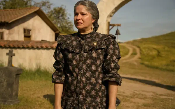 A powerful scene from the TV show One Hundred Years of Solitude, featuring a woman in a vintage dress standing in a rural setting, evoking themes of memory and solitude.