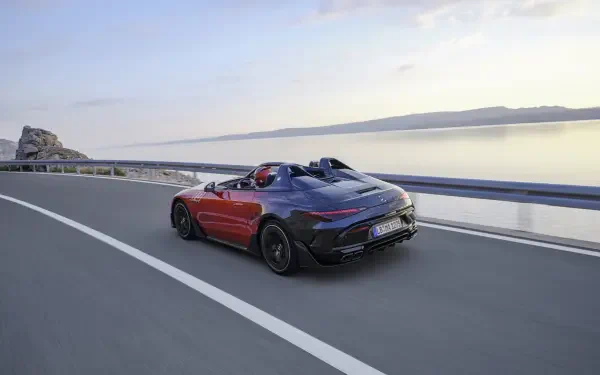 A Mercedes-AMG PureSpeed car driving along a scenic road by the water, showcasing sleek design and performance in a stunning 4K Ultra HD background.