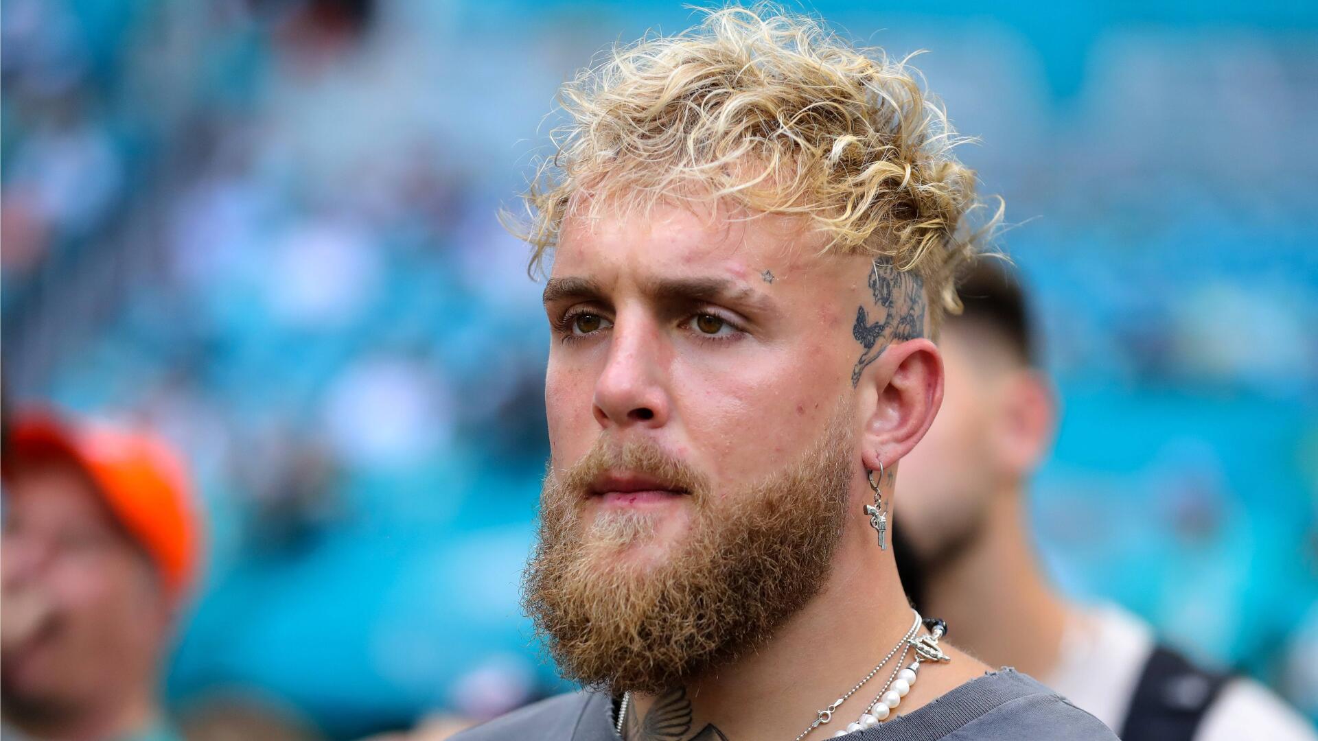 A close-up of a young man with curly hair and a beard, exuding confidence. The image serves as a striking 4K Ultra HD wallpaper featuring popular YouTuber Jake Paul.