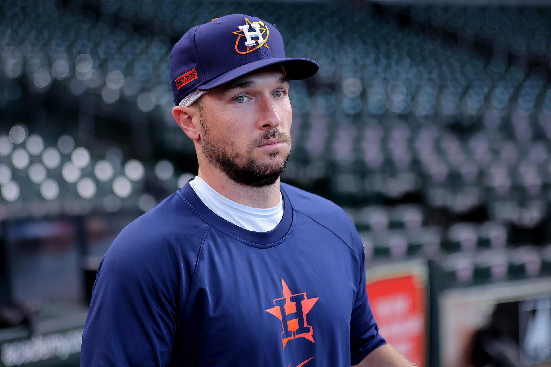 Alex Bregman of the Houston Astros stands focused in a baseball stadium, wearing his team uniform and hat, captured in a high-definition wallpaper celebrating MLB.