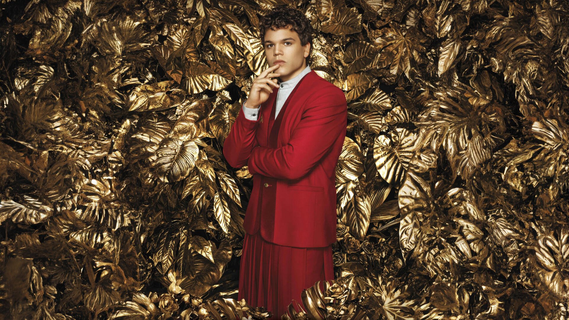 8K Ultra HD PC desktop wallpaper: a figure in a red suit poses amid metallic gold foliage — promotional image for The Hunger Games: The Ballad of Songbirds & Snakes.