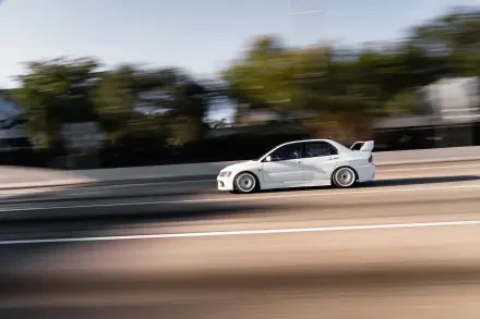 White Mitsubishi Lancer Evolution IX speeding along a sunlit highway with motion-blurred background — 8K Ultra HD PC desktop wallpaper