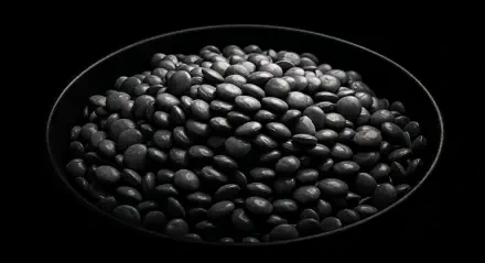 A close-up of a pile of black lentils in a dark plate, set against a black background, showcasing texture and detail. This striking image serves as a 4K Ultra HD PC desktop wallpaper.