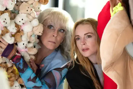Jamie Lee Curtis and Lindsay Lohan peeking from behind a wall of stuffed animals in a scene from the movie Freakier Friday. This image serves as a vibrant 4K Ultra HD wallpaper.