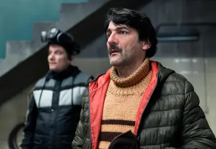 Scene from the TV show The Eternaut, featured as a 4K Ultra HD PC desktop wallpaper, showing two men in winter clothing indoors.