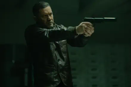 Tom Hardy in an intense scene from the TV show MobLand, captured in 8K Ultra HD, featuring him aiming a handgun in a dark, suspenseful setting.
