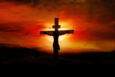 HD PC desktop wallpaper showing Jesus on the cross silhouetted against a fiery orange-red sunset — a Bible crucifixion religious scene.