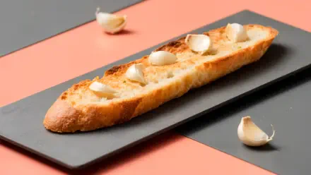 4K Ultra HD PC desktop wallpaper and background: close-up of a garlic bread baguette on a black slate with scattered garlic cloves over pink and gray panels.