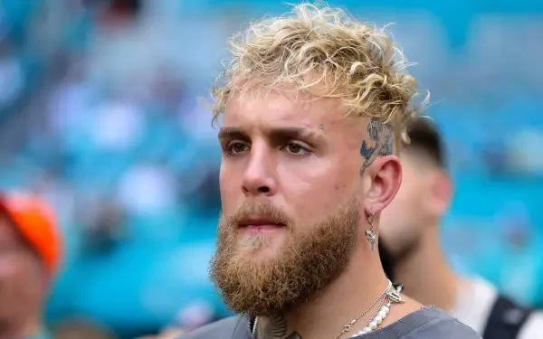 A close-up of a young man with curly hair and a beard, exuding confidence. The image serves as a striking 4K Ultra HD wallpaper featuring popular YouTuber Jake Paul.