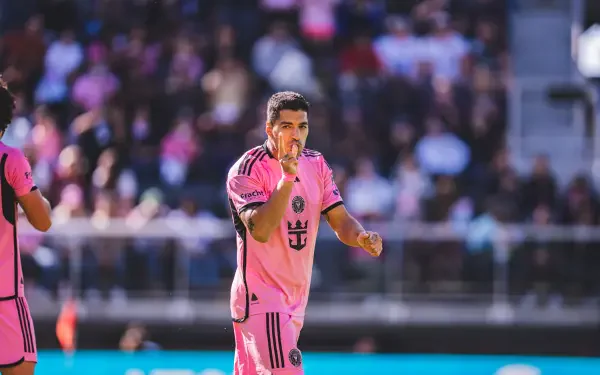 Luis Suárez celebrates during a soccer match with Inter Miami CF, wearing the team's distinctive pink jersey. The vibrant 8K Ultra HD image captures the excitement of the game.