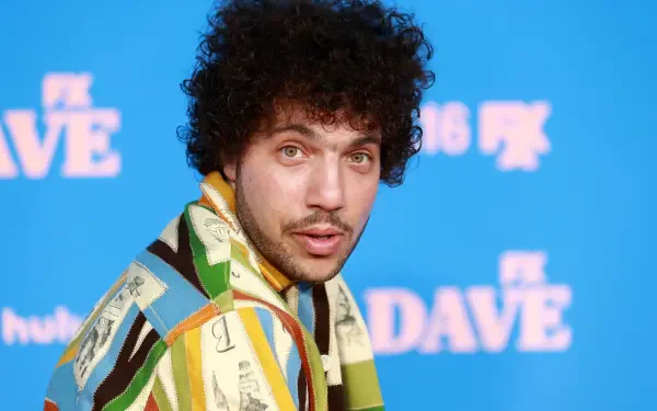 A vibrant HD desktop wallpaper featuring Benny Blanco, showcasing his distinctive fashion and engaging expression against a bright blue background.